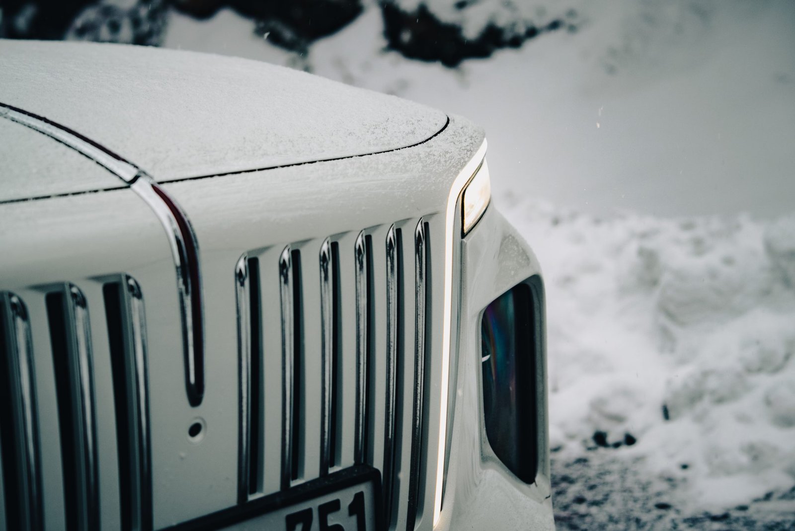 Close crop of an upright chrome grille holding fresh snow